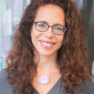 Julie Skolnick headshot in front of colorful background.