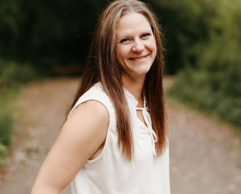 Photo of Karen Beckmann on a country path in front of trees.
