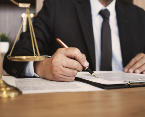 A lawyer signing a contract next to a scale on a table.